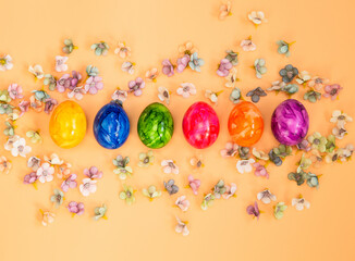 Colorful Easter eggs homemade painted top view flatlay on pastel orange peach background bright fresh design, Happy Easter, spring concept