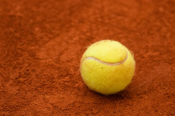 Tennis ball in classic fluorescent yellow lies on the surface of a tennis court