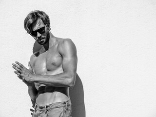 Portrait of sporty handsome strong man. Healthy athletic fitness model posing near white wall in...