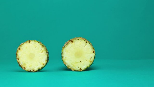 rolling pineapple slicing on turquoise color background and move to plate