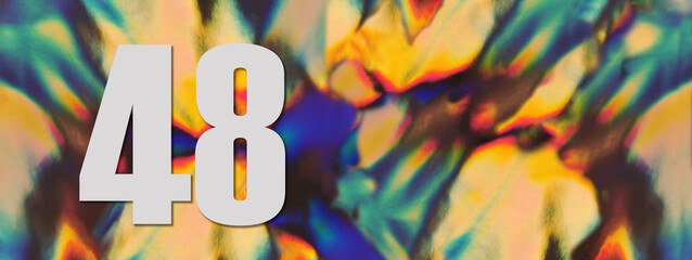 Wide banner. Number 48 forty eight on the blurry iridescent holographic foil background. Colorful reflective folia. Greeting card. Copy space. Flat lay.