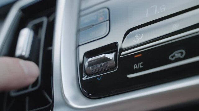 Hand adjusts the air conditioner control buttons in the car. The climate control buttons are silver. The climate system in automatic mode. The Man Regulates The Climate Control In The Car