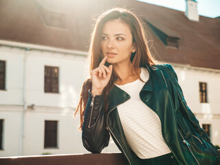 Portrait of beautiful smiling model. Female dressed in summer hipster black leather jacket and jeans. Trendy woman posing on the street background. Having fun in outdoors