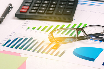 Obraz premium Accounting and finance. Desktop with documents. Profit growth charts, black-rimmed glasses, calculator and pen. Business concept. Work at home or in the office. Report preparation, data analysis