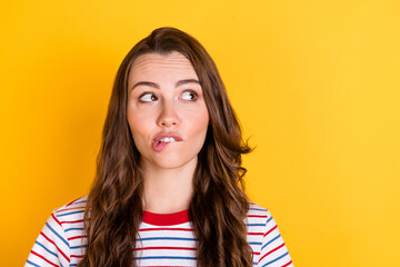 Photo of sweet doubtful young woman wear striped outfit biting lip looking empty space isolated...