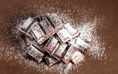 Dark chocolate in powdered sugar. Chunks of dark chocolate.