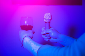 Man holding wine glasses and microphone. Night party, have fun, karaoke singing.