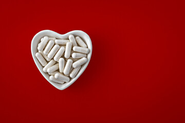 close-up of lithium orotate capsules. dietary concept: an porcelain bowl in the form of a heart full of lithium orotate capsules. dietary supplement topview