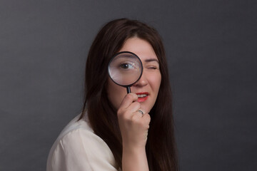 A brunette woman with long hair, wearing a beige blouse on a gray studio background