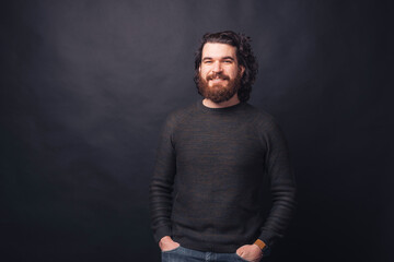 Portrait of handsome bearded hipster man over black background