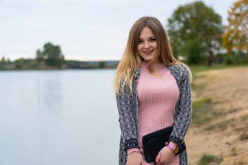 A young girl poses with a handbag posing in a warm autumn evening.