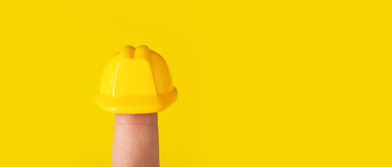 helmet on finger over yellow background, construction hard hat for head, panoramic image