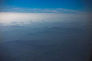 Blurred abstract background from high angle from plane window, overlooking the scenery below (river, mountain, tree).