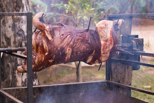 Pork barbecue on a rotating spit. Barbecue and smoking. Horizontal photography Gourmet Gastronomy.
