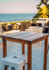 Mesa alta con taburete en una terraza frente al mar
