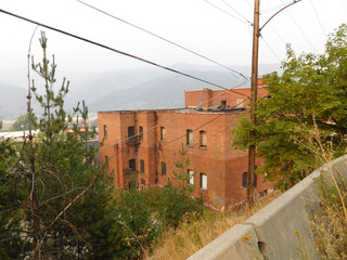 Fototapeta na wymiar The back view of a red brick building in Keoogg, Idaho. Fog almost obscures the adjacent mountains in the distance.