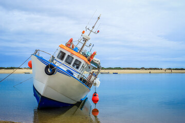 Fishing boat stranded due to low tide in Ria Formosa Nature reserve - Fuseta, Olhão - Algarve,...