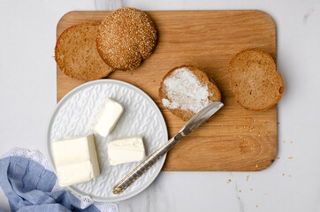 Top view of delicipus rye bun with butter on the wooden board.Traditional rustic breakfast