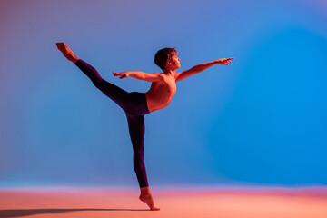 teenage ballet dancer dances barefoot under colored light.