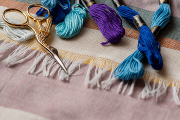 Skeins with floss threads and scissors on fabric surface. Hobbies and recreation, embroidery...