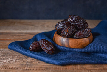 royal dates in a bowl on a blue tablecloth on a wooden table with copy space