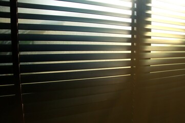 Evening sun light outside wooden window blinds, sunshine and shadow on window blinds , decorative interior home concept
