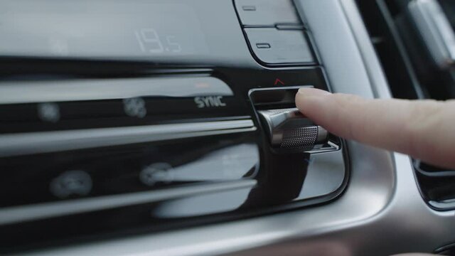 Hand adjusts the air conditioner control buttons in the car. The climate control buttons are silver. The climate system in automatic mode. The Man Regulates The Climate Control In The Car