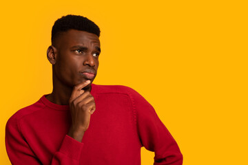 Doubtful Young Black Man Looking Aside At Copy Space With Curiousity
