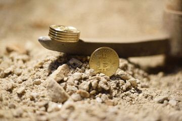 Coins found in bitcoin mine with pickaxe and rocks, conceptual image bitcoin mining.