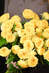A bouquet of yellow roses in the woman's hands close-up.