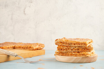 Stacked portions of an empanada with natural ingredients such a tomato, onion, pepper, tuna, egg and dough of wheat on a wooden plate. Tuna pie. Typical Galician dish from Galicia and Spain