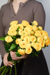 A bouquet of yellow roses in the woman's hands close-up.