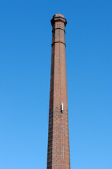 Tall Brick Industrial Chimney seen from  Below against Blue Sky