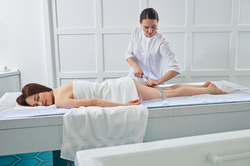 Fototapeta premium Female on a massage couch enjoying gua sha leg massage