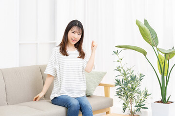 部屋のソファでガッツポーズをする若い女性