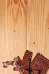broken bar of chocolate on wooden background texture sweets