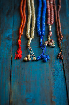 Various types of prayer beads or rosaries placed in a row on dark blue background. Conceptual image for religious harmony and togetherness.