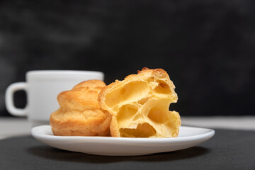 Homemade profiteroles for tea. Puffs, popovers, eclairs on black background.