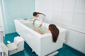 Spa employee concentrating water jet on visitor foot