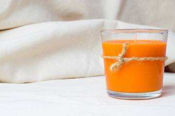Orange scented candle, 
refreshing decoration, on white cotton fabric