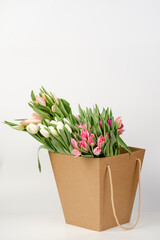 Lots of pink, white and salmon tulips in crafting packaging close-up on a white background.