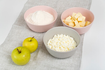 Ingredients for Apple Pie. Plates with flour, butter, cottage cheese and apples.