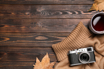 Flat lay composition with cup of hot tea and autumn leaves on wooden background. Space for text