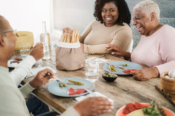 Happy black family eating lunch at home - Father, daughter, son and mother having fun together sitting at dinner table - Main focus on mum face