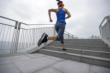 Healthy lifestyle fitness sports woman runner running up stairs on seaside trail