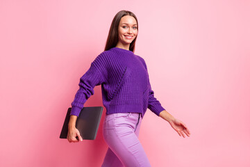 Profile portrait of adorable lady walking hold netbook look camera wear pullover isolated on pink color background © deagreez