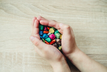 children's hands are holding colorful pebbles