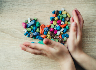 children's hands are holding colorful pebbles