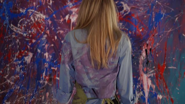Blonde woman reflecting in front her artwork in workshop, rare view