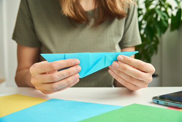 DIY concept. Woman make origami easter rabbit from color paper. Origami lessons